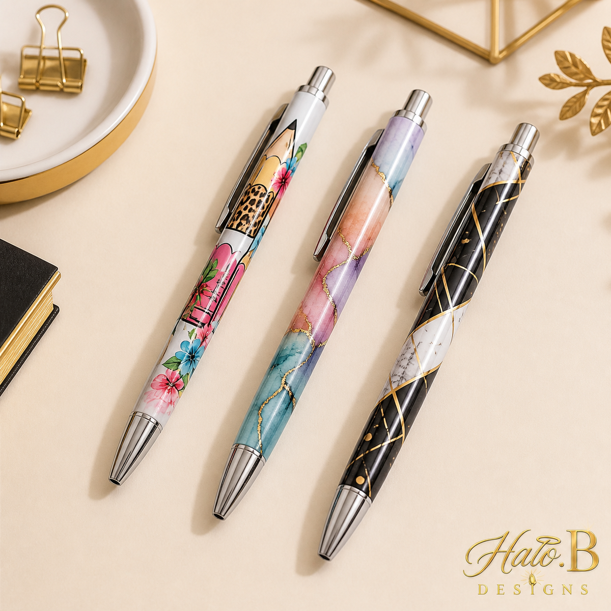 Three custom image-printed pens with floral watercolor and black-gold designs and new gold Halo B Designs watermark